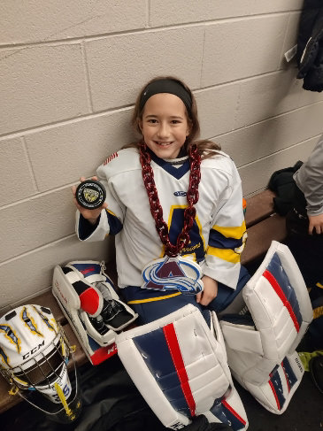 Emma Preston, of the Arapahoe Warriors 10U Yellow team, proudly holds up the game puck after another big game.
